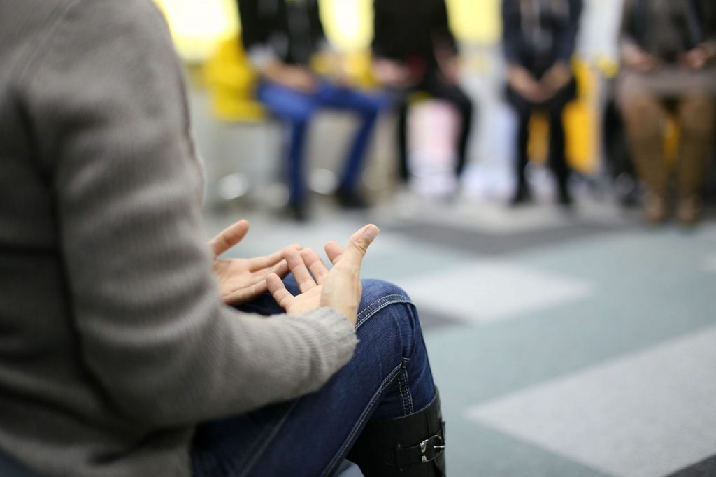 Group Sessions - grup sat in distance with person with hands out on lap